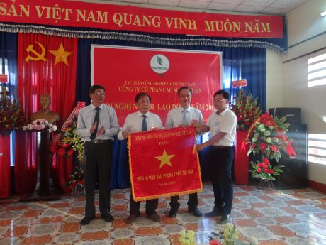 Ông Nguyễn Tiến Đức – Phó TGĐ VRG (ngoài cùng bên trái) và ông lâm Xuân Thao – Chánh Văn phòng Tổng lãnh sự quán Việt Nam tại 4 tỉnh Nam Lào (ngoài cùng bên phải) trao tặng cờ thi đua xuất sắc của Chính phủ cho Công ty CP Cao su Việt Lào.