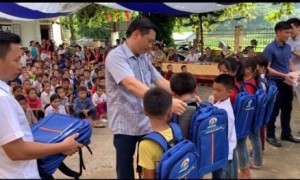 Đại diện lãnh đạo Tập đoàn Quế Lâm trao quà cho các em học sinh.